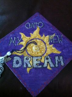 a purple and yellow graduation cap with the words, my new dream on it's side