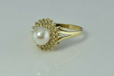 "14K Yellow Gold Pearl and Diamond Halo Ring, 7.5mm white pearl green and pink lustre, 2 rows of diamonds, halo .5\" across ring, Ring size 6.5, Circa 1970, 3.6 grams Stock # BB234R24 Most rings are sizable for a small fee. If the ring you are considering is the incorrect size contact us for a quote. This listing contains photographs of the actual item you will receive. Our items are in excellent condition with little or no signs of wear and many are one of a kind pre-owned estate finds. Please Formal Pearl Ring With Diamond Halo Design, Formal Diamond Pearl Ring With Halo Design, Elegant Cluster Halo Ring As A Gift, Formal Diamond Pearl Ring With Halo, Formal Diamond Halo Pearl Ring, Elegant Cluster Halo Ring, Formal Round Cut Halo Pearl Ring, Luxury Formal Pearl Ring With Halo, Formal Fine Jewelry Pearl Ring With Halo Design