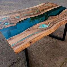 a table made out of wood with blue glass in the center and black metal legs