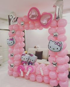 a hello kitty balloon arch in a living room decorated with pink balloons and other decorations