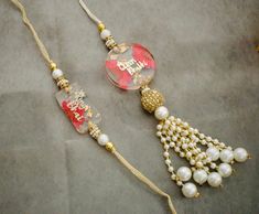 two necklaces with pearls and beads on a gray tablecloth, one is red and the other is gold