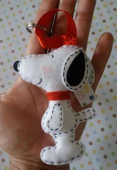 a hand holding a small stuffed dog in it's right hand with a red ribbon around its neck