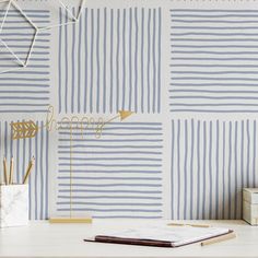 a desk with a notebook, pen and pencil holder on it next to a wallpaper