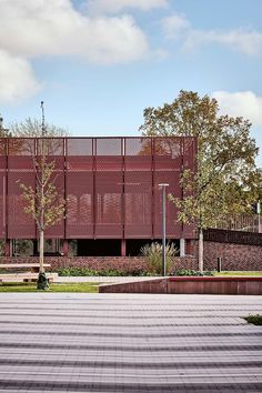 an empty parking lot in front of a building with a red metal structure on it