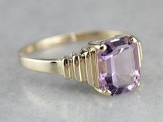 Outstanding! This modern yellow gold setting perfectly frames the amethyst we've set at the center! The tapering stepped yellow gold band looks soft and elegant on the finger, while the rich purple gem glitters with violet sparkles! Metal: 14K Yellow Gold Gem: Amethyst 2.85 Carats Gem Measurements: 7.8 x 9.9 mm, Emerald Cut Ring Size: 10 Marks: "14K UP" Stamped on the inside band Modern Yellow Gold Amethyst Ring For Wedding, Modern Yellow Gold Amethyst Wedding Ring, Gold Solitaire Amethyst Ring For Formal Occasions, Ring With Baguettes, 10 Marks, Emerald Cut Ring, Purchasing Power, Purple Gems, Emerald Cut Rings