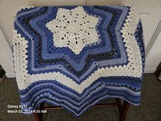 a blue and white crocheted blanket sitting on top of a chair