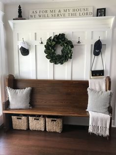 a wooden bench sitting in front of a wall with two wreaths on top of it