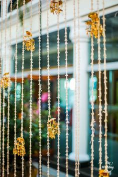 the window is decorated with beads and gold decorations on it's glass rods