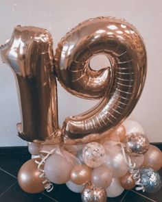 the number twenty nine is surrounded by balloons and streamers in gold, silver and white colors