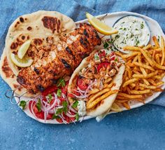 a plate filled with tacos, chicken and french fries on top of a blue cloth