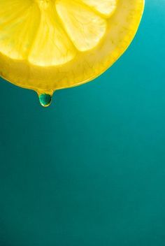 a slice of lemon sitting on top of a blue surface with water drops coming from it