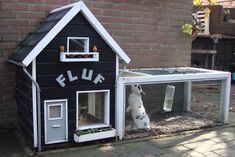 a black and white dog house with a rabbit in it's cage next to a brick wall