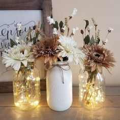 three mason jars filled with flowers and lights