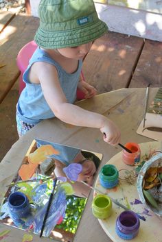 a little boy painting on a table outside