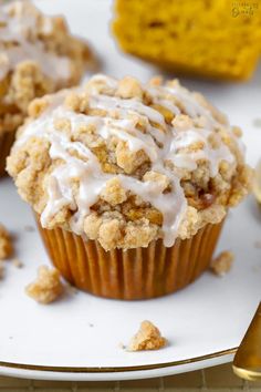 a muffin with white icing sitting on a plate next to other muffins