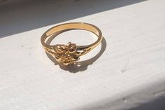 This delicate 10k yellow gold flower ring is a timeless piece that adds a touch of nature-inspired elegance to any outfit. Handcrafted with care, the simple floral design symbolizes beauty, growth, and new beginnings, making it a perfect gift for someone special--or a lovely treat for yourself. The ring features a finely detailed flower at its center, resting on a slim, polished band that's comfortable for everyday wear. Its minimalist style makes it versatile enough to be worn alone or stacked with other rings for a more personalized look. Delicate Gold Flower Ring For Formal Occasions, Classic 14k Gold Flower Ring, Gold Flower Ring With Charm For Wedding, Formal Yellow Gold Flower Ring, Classic Gold Flower Ring, 14k Gold Formal Flower Ring, Formal 14k Gold Flower Ring, Dainty Flower Ring For Formal Occasions, Dainty Yellow Gold Flower Ring For Anniversary