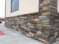 the corner of a building with a stone wall and red fire hydrant next to it