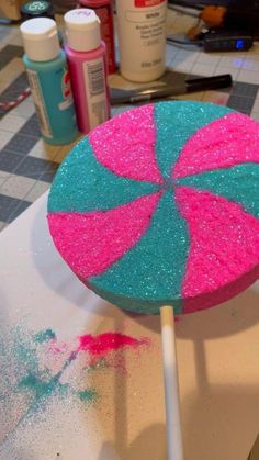 a lollipop sitting on top of a table covered in pink and blue sprinkles