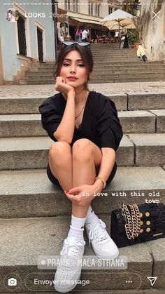 a woman sitting on the steps with her hand under her chin