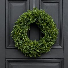 a green wreath is hanging on the front door