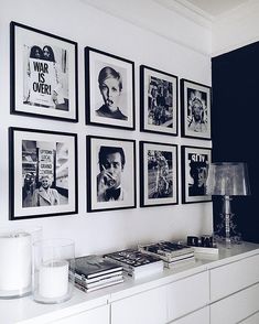 black and white photographs hang on the wall above a dresser in a room with posters