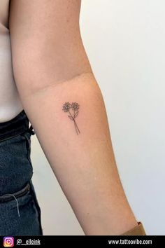 a woman's arm with a small flower tattoo on the left side of her arm