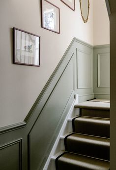 some stairs with pictures on the wall and carpeted steps leading up to them in a home