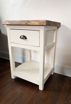 a small white table with a drawer on it's side next to a wall