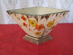 a decorative vase sitting on top of a red tablecloth covered table next to a wall