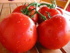 four tomatoes sitting on top of a wooden table