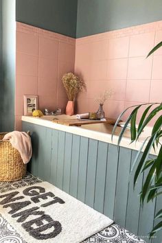 Bath tub with tiles painted pink and green paint on walls and tub. Black and white patterned tile. "GET NAKED" bath mat. Pink And Green Ensuite, Pink And Green Washroom, Bathroom With Pink Tub And Sink, Peach Bathroom Suite, Peach And Teal Bathroom, Peach Tiles Bathroom, Pink Bathroom Tiles Color Schemes, Coral And Green Bathroom, Pink Tile Bathroom Ideas Color Schemes