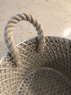 a close up of a metal basket with rope on the top and bottom, in front of a concrete floor