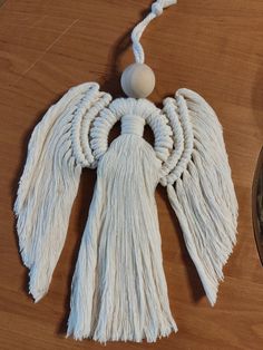 a white tasseled angel ornament sitting on top of a wooden table