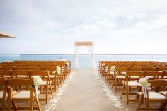 an outdoor wedding ceremony setup with chairs and flowers on the aisle, overlooking the ocean