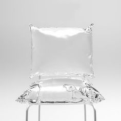 a glass chair with a pillow on top of it