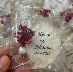 a person holding a piece of glass with flowers and pearls on it in their hand