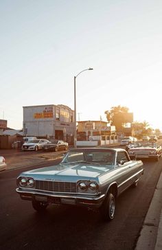 an old car is parked on the side of the road in front of other cars