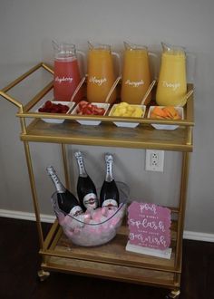 a gold bar cart filled with drinks on top of a hard wood floor