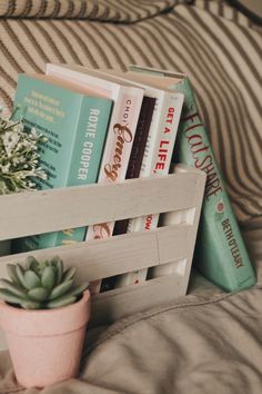 a wooden crate filled with books on top of a couch next to a potted plant