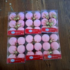 four boxes filled with pink donuts on top of a wooden table