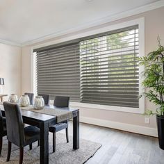 a dining room table and chairs with blinds on the windows