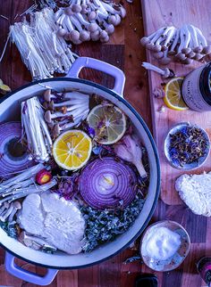 a pot filled with food sitting on top of a wooden table next to garlic and lemons