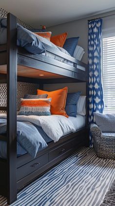 bunk beds with blue and orange pillows in a small bedroom area next to a window