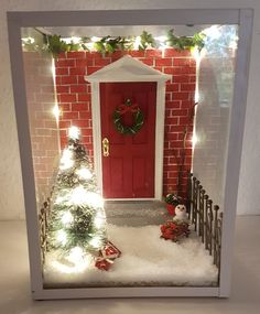 a small christmas scene with a red door and snow on the ground in front of it