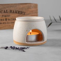 a white ceramic candle holder sitting next to a wooden box and lavender sprig