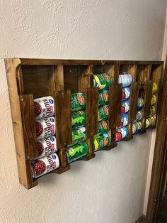 a wooden spice rack filled with lots of different types of canned food and drinks on it