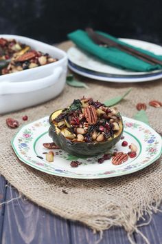 a white plate topped with a stuffed acorn filled with nuts and other food items