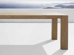 a wooden table sitting on top of a white floor next to a wall and ocean