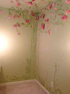 a bathroom with pink flowers painted on the wall and a tree mural in the corner