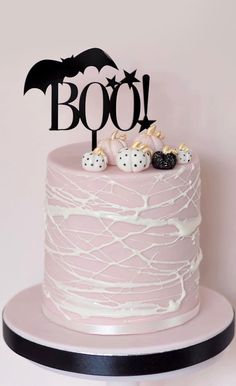 a pink cake with white icing and black bats on top that says booj